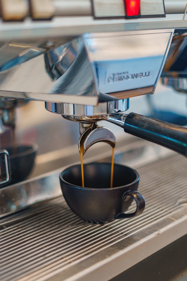 Un espressor din care curgea cafea intr-o ceasca care arata ce inseamna cafea barista